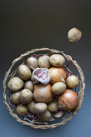 Mix raw potatoes garlic cloves and onion in brown basket