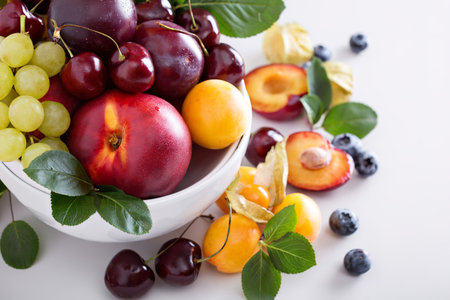 Fresh stone fruits cherries peaches plums in white bowl