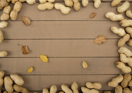 top view of peanuts in shell scattered on wooden background with copy space