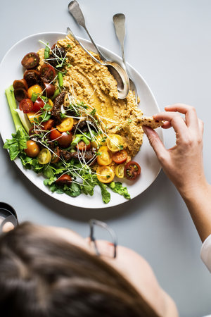 Woman dipping crackers in a hummus saladの写真素材