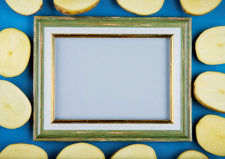 top view of potato slices around frame on blue background with copy spaceの写真素材