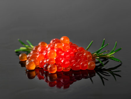 A handful of red caviar on a dark background with a reflection. Gourmet food, seafoodの写真素材