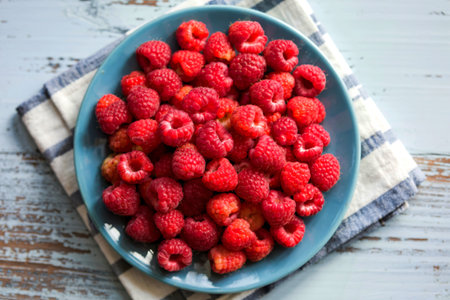 Blue plate full of juicy,delicious, healthy raspberriesの写真素材