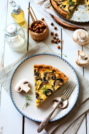 Mushroom, champignon pie, quiche slice on a ceramic plate on a white wooden backgroundの写真素材