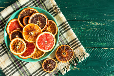 top view of dried grapefruit slices in a plate on plaid tableclothの写真素材