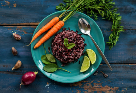 Black rice in plate with vegetable carrot has spoon isolated on blue wood backgroundの写真素材