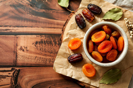 top view of dried apricots in a bowl and with dried dates on wooden background with copy spaceの写真素材