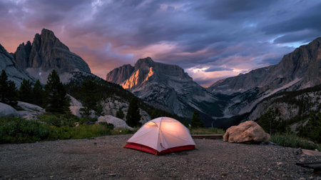 Tent at camp site in the middle of rocky mountains with cloudy skyの写真素材