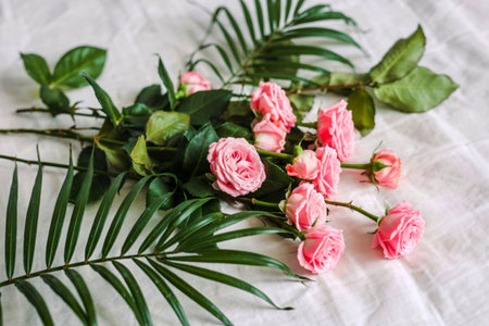 side view of pink color roses on a palm leaf on white background