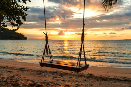 Wood swing with palm tree on the tropical beach sunset over the sea for travel in holiday relax timeの写真素材