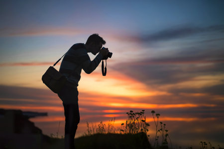 Photographer silhouetted against vibrant sunsetの写真素材