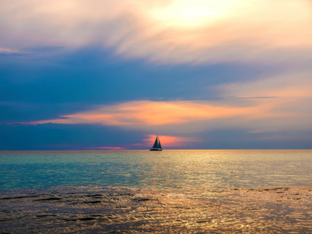 Sailboat at sunset on calm ocean watersの写真素材
