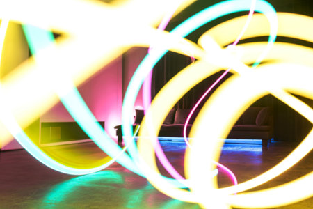 Blurred neon light trails in vibrant colors create an abstract design, partially obscuring a modern...