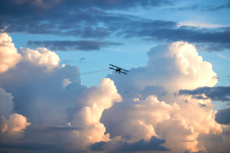 A single biplane flies through a vast expanse of fluffy cumulus clouds, leaving a faint contrail in...