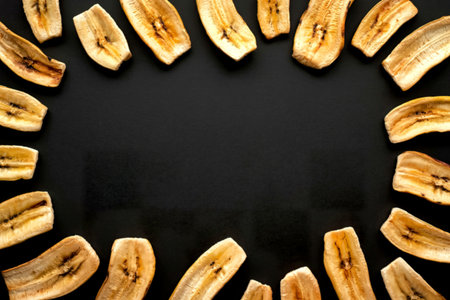 top view of dried banana chips isolated on black background with copy space