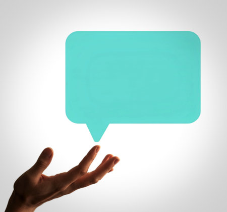 A person's open hand is presented upwards, as if offering or holding a large, blank, teal speech bubble. This symbolizes communication, ideas, or messages.の写真素材