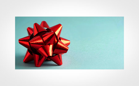 A close-up shot of a metallic red gift bow with multiple loops, positioned on the left side of a...