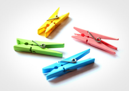 Four brightly colored wooden clothespins, yellow, green, pink, and blue, are arranged diagonally on...