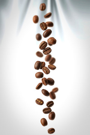 A vertical image showcases numerous roasted coffee beans falling against a clean white backdrop. The beans appear to be in mid-air, creating a dynamic and visually appealing composition.の写真素材
