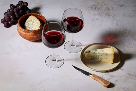 A sophisticated spread featuring red wine, cheese, and grapes, perfect for a relaxed tasting or elegant gathering.の写真素材