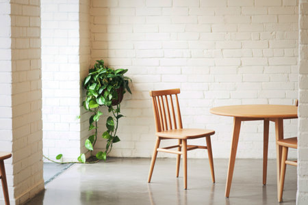 A bright, airy dining space featuring two simple wooden chairs and a light-colored table, with a...