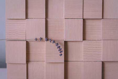 A close-up view of a textured, light-colored wooden surface with a small, delicate twig adorned with tiny flowers.の写真素材