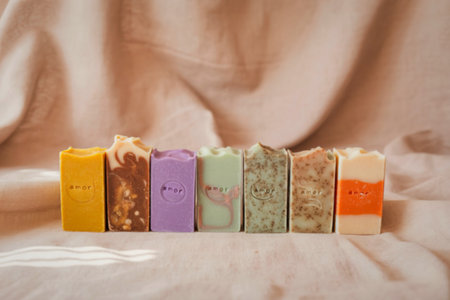 A collection of colorful, artisanal soaps with visible ingredients like herbs and oats, arranged in a row.の写真素材