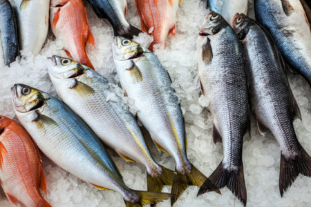 A variety of fresh fish laid out on a bed of ice, showcasing different types of seafood ready for...