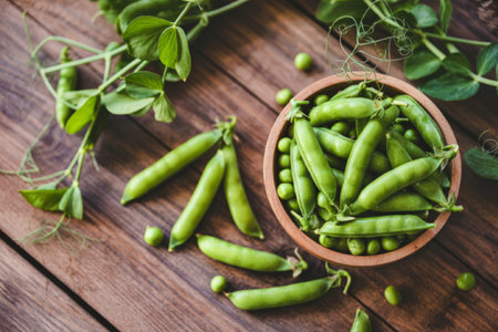 A close-up image of fresh green peas in a wooden bowl placed on a rustic wooden table. Surrounding...