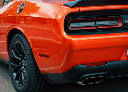 A sleek, bright orange sports car is captured from the rear, showcasing its modern design and...