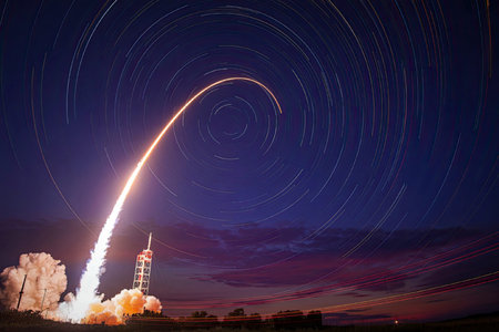 A rocket launch is captured with a long exposure, showing its trajectory and the star trails in the...