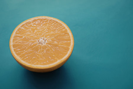 A vibrant orange slice displayed on a solid blue surface, highlighting its juicy texture and freshness.の写真素材
