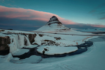 a serene snowy landscape featuring a majestic mountain and a beautiful waterfallの写真素材
