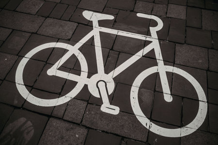 A white painted bicycle symbol on a dark brick pavement indicating a bicycle lane.の写真素材