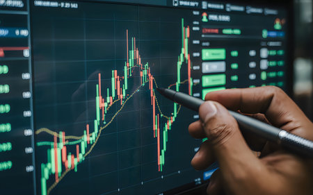 A person analyzing a stock market graph on a computer screen with a pen.