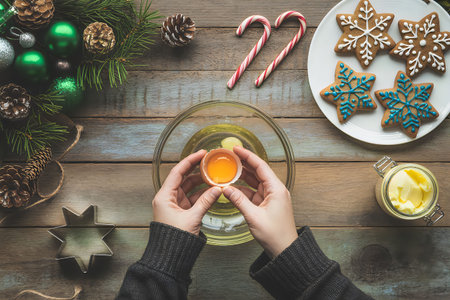 A person holding a mug of mulled wine next to a Christmas tree, candy canes, and holiday cookies.