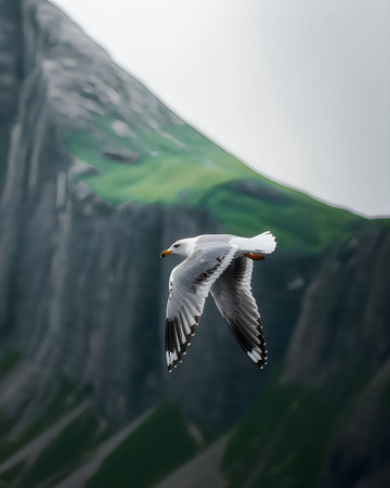 A seagull flies over a rugged mountainous landscape with lush greenery and a cloudy sky.