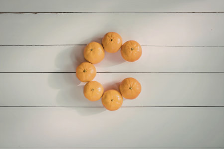 A circle of oranges on a white wooden surface, possibly a table or floor.の写真素材