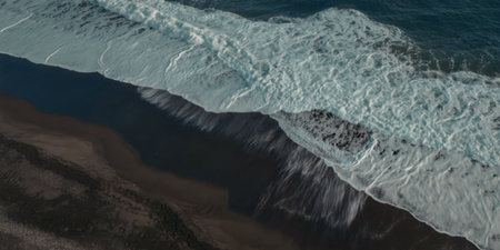 A wave crashes onto the shore, creating a foamy texture on the water's surface.