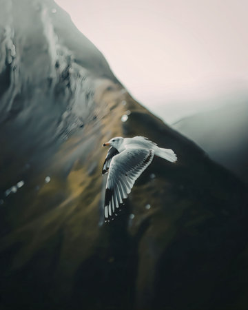 A bird in flight soaring over a mountain with a blurred backgroundの写真素材