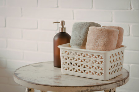 A brown bottle and towels in a basket on a table