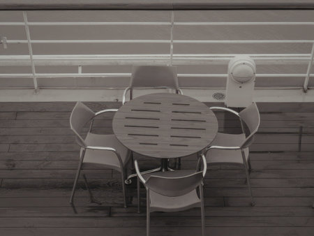 A simple outdoor scene with a round metal table and four chairs on a patio.