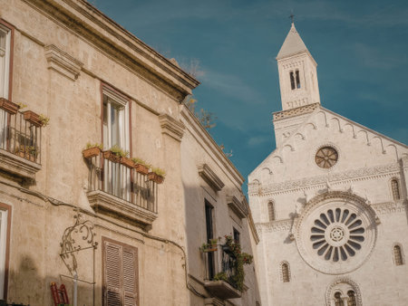A charming historic stone church with a clock tower and an old building nearby, set against a blue sky.