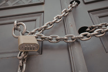 A close-up view of a gray door secured with a chain and padlock, emphasizing security and restriction.