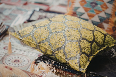 A close-up view of a yellow embroidered pillow resting on a collection of vibrant textiles and patterns.