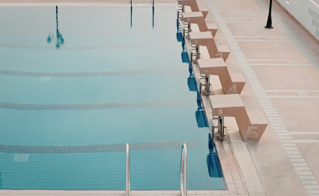 a large outdoor swimming pool with multiple lanes and diving blocks on the side, the pool is empty and the water is calm and clear