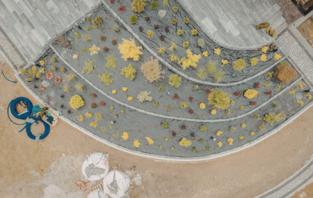 an aerial view of a garden with multiple levels of plants and a blue hose on the left side of the image. there are also some white bags with soil or mulch.