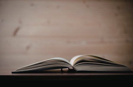 An open book lying on a dark brown table with a blurred wooden background