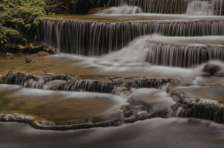 A serene waterfall cascading down multiple tiers, surrounded by lush greenery.