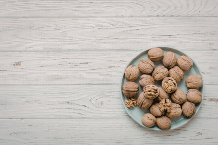 A plate of walnuts placed on a white wooden table, showcasing the nuts as the main focus.